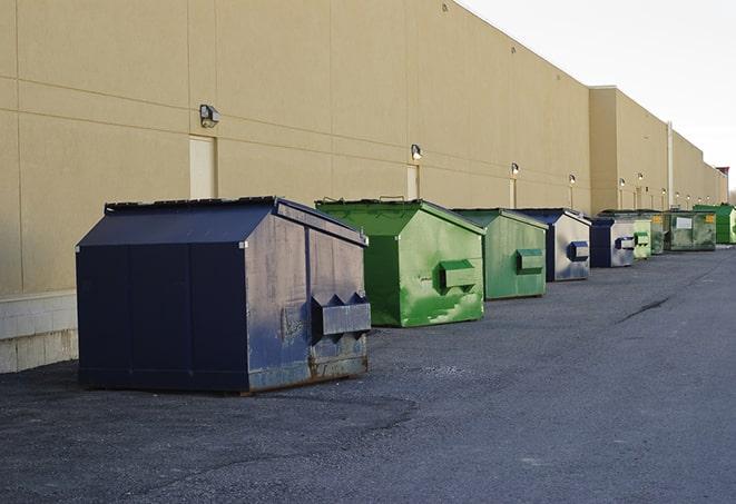 a construction worker empties a wheelbarrow of waste into the dumpster in Allentown NJ